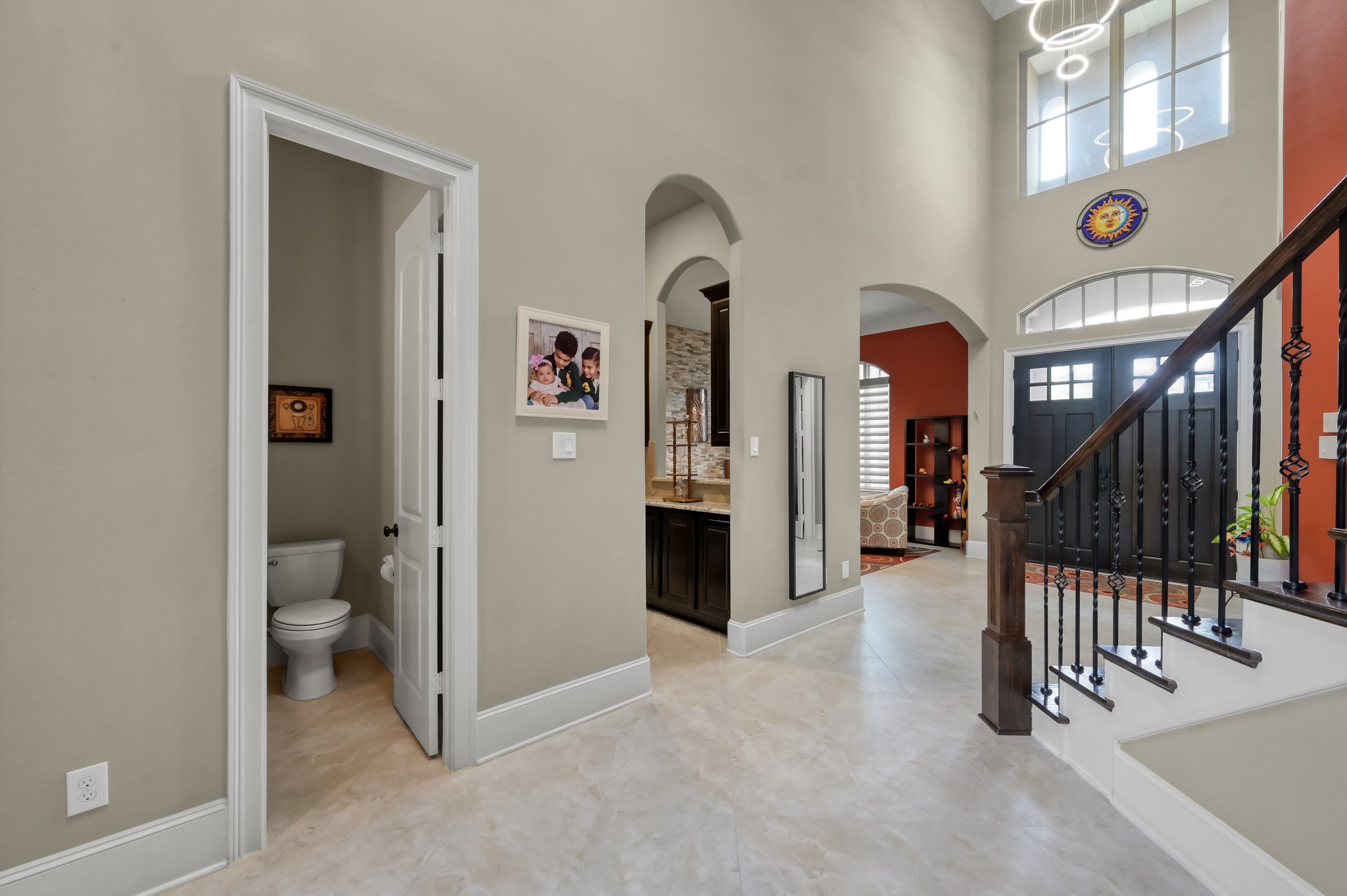 26 Woodborough Way Spring, TX 77389 - Photo 5 of 43 This photo showcases a welcoming foyer with high ceilings and natural light. The entrance features a staircase with decorative railing, a half-bathroom, and a view into a cozy living area. Neutral tones and modern lighting add elegance.