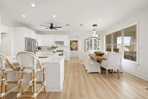 a very nice looking dining room with kitchen island stainless steel appliances furniture a fireplace and a chandelier