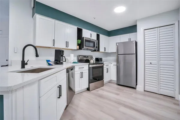 a kitchen with white cabinets and stainless steel appliances