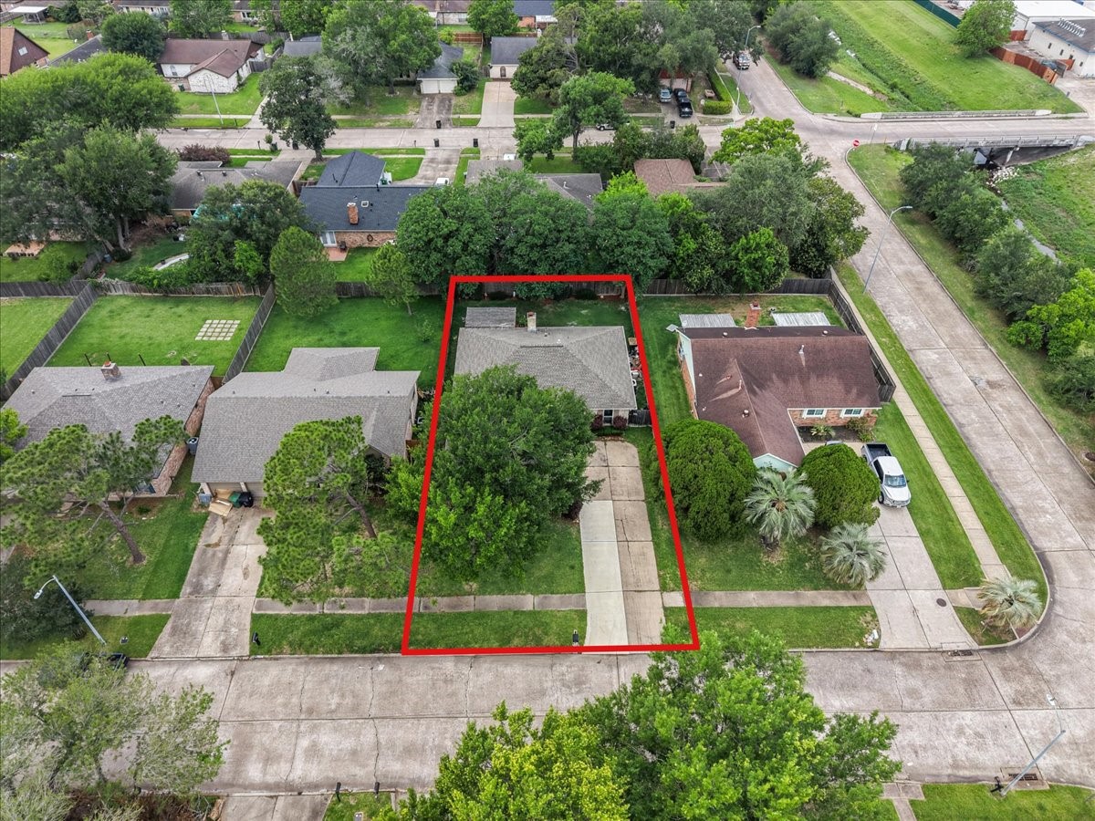 883 Silverpines Road Houston, TX 77062 - Photo 3 of 38 This aerial photo showcases a charming single-story home outlined in red. It's nestled in a lush, green neighborhood with mature trees. The property features a long driveway and a spacious backyard, perfect for outdoor activities.