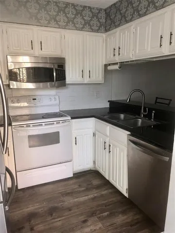 a kitchen with granite countertop white cabinets stainless steel appliances and sink
