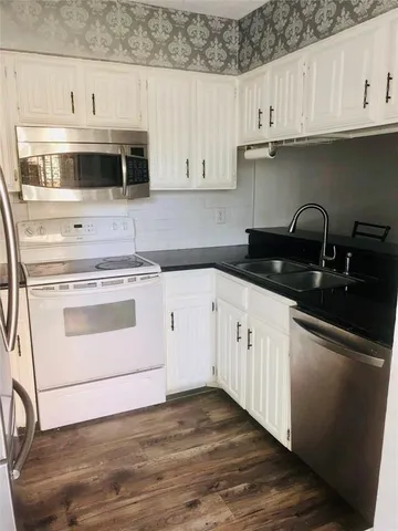 a kitchen with granite countertop white cabinets and white appliances