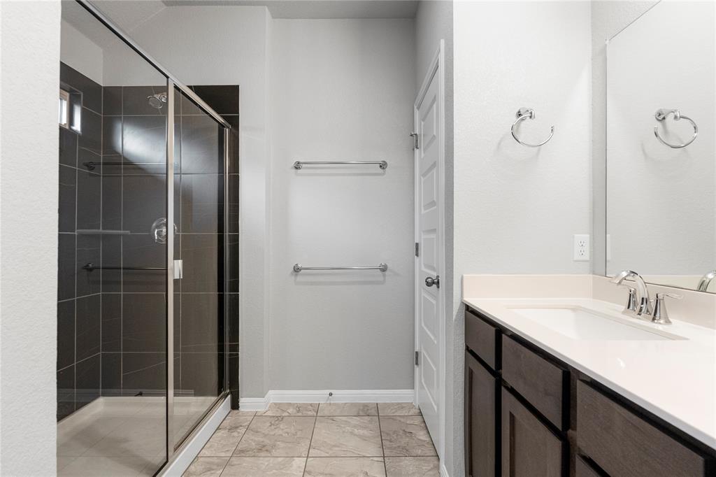 4719 Portillo Way Pflugerville, TX 78660 - Photo 12 of 27 A glass-enclosed walk-in shower and a modern vanity define this pristine bathroom.
