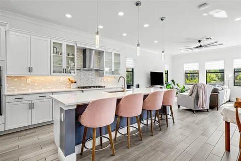 a open kitchen with stainless steel appliances granite countertop a table chairs sink refrigerator and cabinets