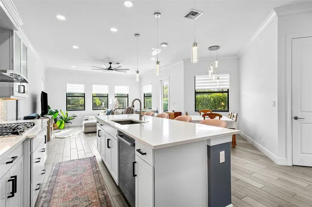 a kitchen with stainless steel appliances a sink stove and wooden floor