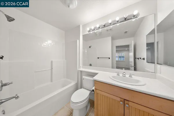 a bathroom with a sink a toilet a mirror a bathtub and shower