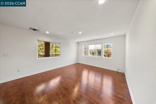 an empty room with wooden floor and windows