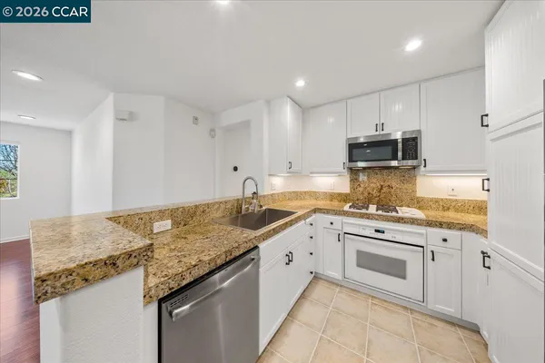 a kitchen with granite countertop white cabinets and white appliances