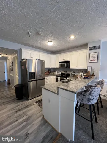 a kitchen with stainless steel appliances granite countertop a refrigerator a stove a sink a dining table and chairs