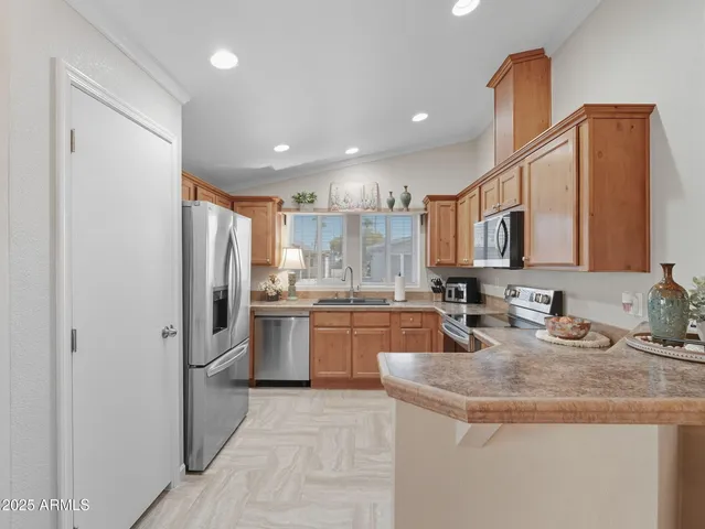 a kitchen with stainless steel appliances granite countertop a sink a stove a refrigerator a washer dryer and a dining table