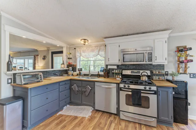 a kitchen with stainless steel appliances granite countertop a stove a sink dishwasher and a microwave oven with wooden cabinets