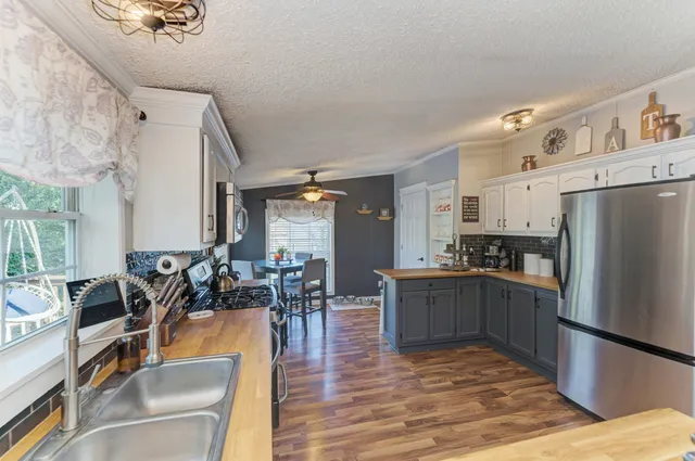 a kitchen with stainless steel appliances granite countertop a refrigerator a stove top oven a dining table and chairs with wooden floor