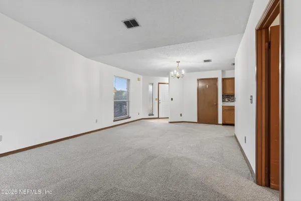 an empty room with kitchen chandelier and windows