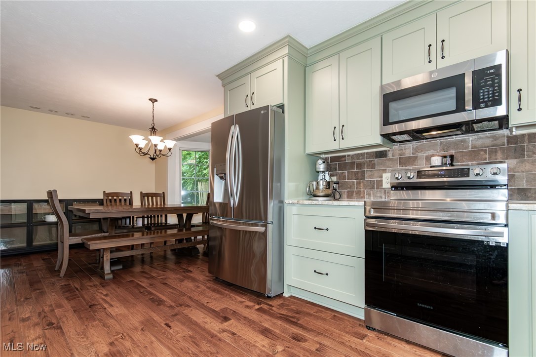 7806 Fairidge Road Willoughby, OH 44094 - Photo 18 of 41 Kitchen featuring appliances with stainless steel finishes, a chandelier, green cabinets, decorative backsplash, and dark wood-type flooring