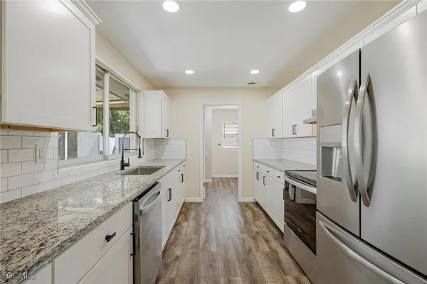 a large kitchen with stainless steel appliances granite countertop a lot of counter space and wooden floors