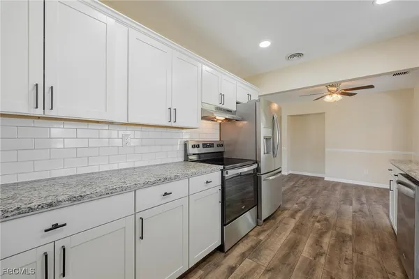 a kitchen with granite countertop a sink stainless steel appliances and cabinets
