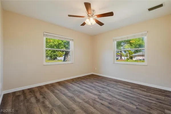 a view of an empty room with window and wooden floor