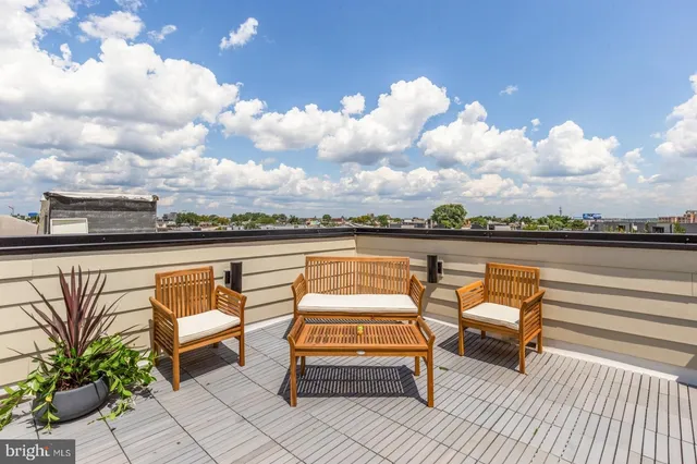 a roof deck with couple of chairs and a potted plant