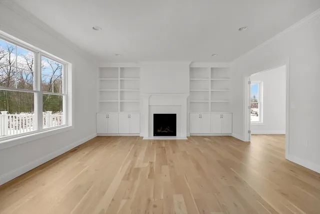 a view of an empty room with a window and wooden floor