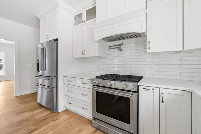 a kitchen with cabinets stainless steel appliances and wooden floor