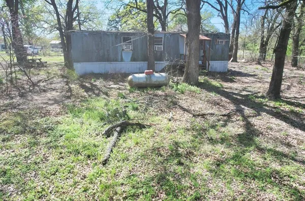 a view of a backyard with large trees and wooden fence