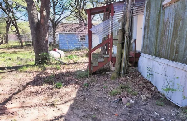 a backyard of a house with large trees and a wooden fence