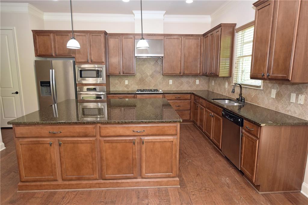 1630 Bramble Bush Way Suwanee, GA 30024 - Photo 3 of 31 a kitchen with stainless steel appliances granite countertop a sink a stove and a refrigerator