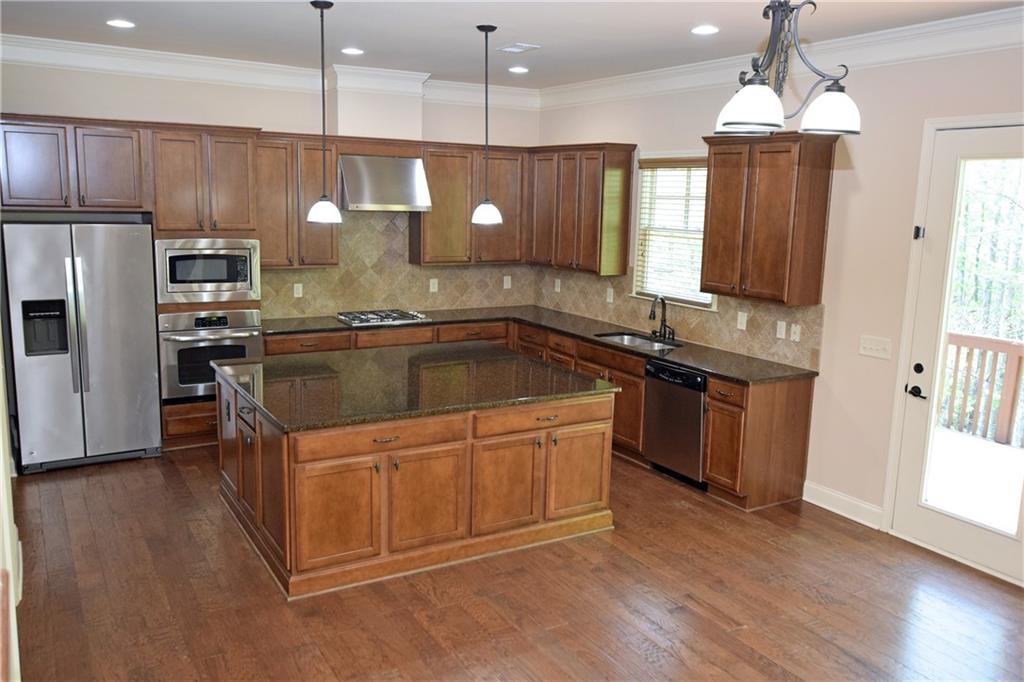 1630 Bramble Bush Way Suwanee, GA 30024 - Photo 9 of 31 a kitchen with kitchen island granite countertop a sink a counter space appliances and cabinets