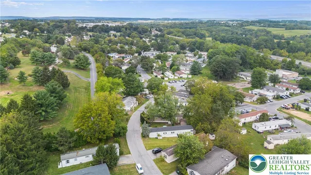 an aerial view of a residential houses with outdoor space and trees