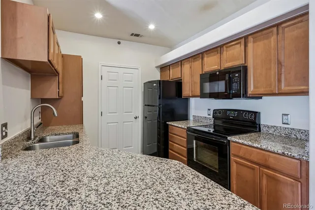 a kitchen with stainless steel appliances granite countertop a refrigerator stove and sink
