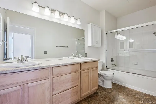 a spacious bathroom with a double vanity sink a toilet and a mirror