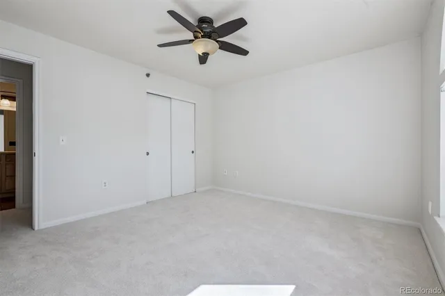 an empty room with a ceiling fan and a window