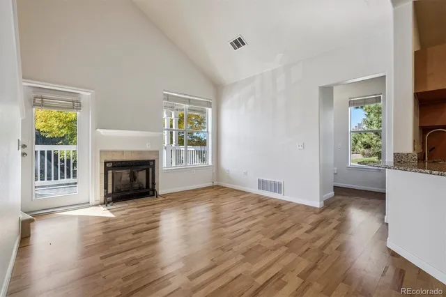 an empty room with windows a fireplace and wooden floor