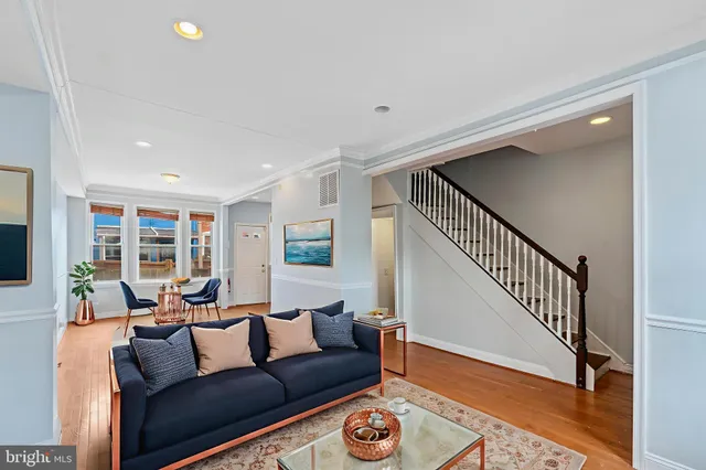 a view of an empty room with wooden floor and stairs