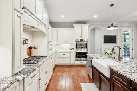 a spacious bedroom with a large bed a chandelier and windows