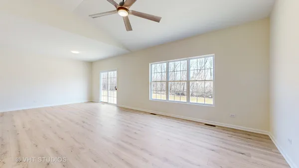 an empty room with wooden floor fan and windows