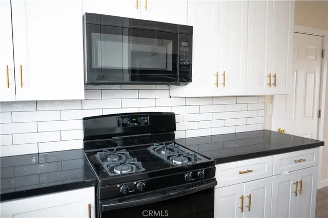 a kitchen with granite countertop a stove and a microwave