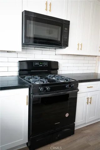 a kitchen with granite countertop a stove and a microwave