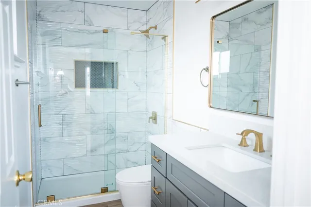 a bathroom with a granite countertop sink a toilet a mirror and shower
