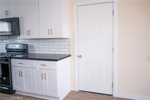 a kitchen with granite countertop white cabinets and black appliances