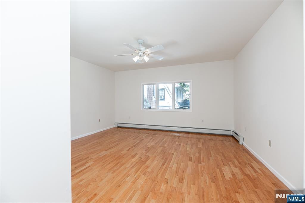 499 Morse Avenue Ridgefield, NJ 07657 - Photo 35 of 45 an empty room with wooden floor chandelier fan and windows