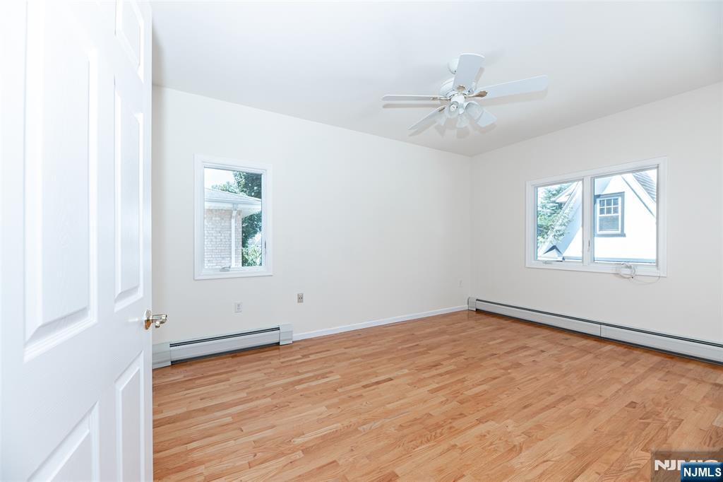 499 Morse Avenue Ridgefield, NJ 07657 - Photo 36 of 45 an empty room with wooden floor chandelier fan and windows