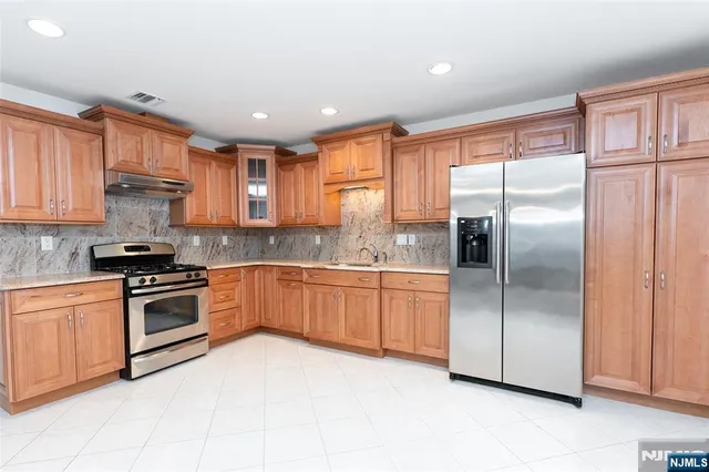 a kitchen with granite countertop stainless steel appliances a refrigerator stove top oven and sink