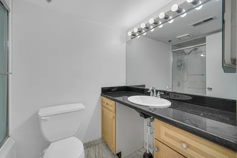 a bathroom with a granite countertop toilet sink and mirror