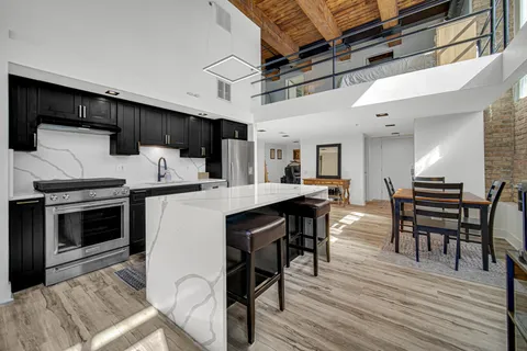 a kitchen with stainless steel appliances kitchen island granite countertop a table chairs and a refrigerator