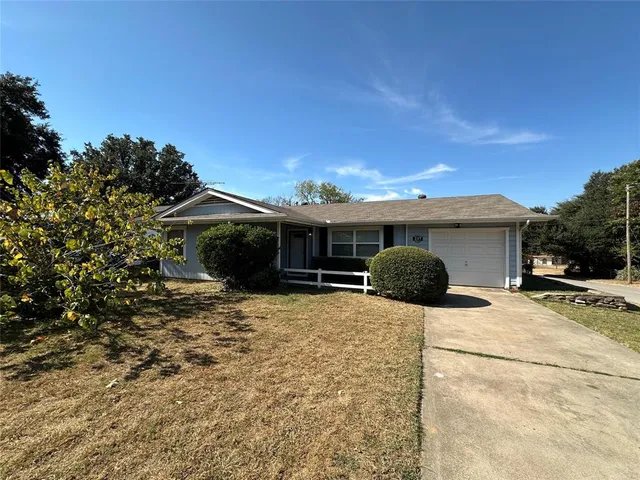 a front view of house with yard and trees in the background