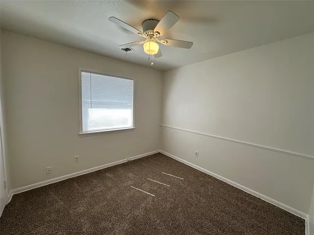 an empty room with a window and a ceiling fan
