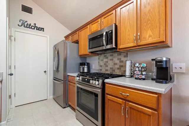 a kitchen with stainless steel appliances granite countertop a stove top oven a refrigerator and a microwave