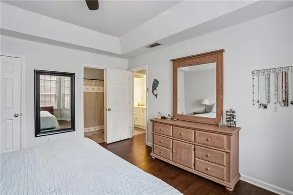 a spacious bedroom with a bed and a mirror on dresser