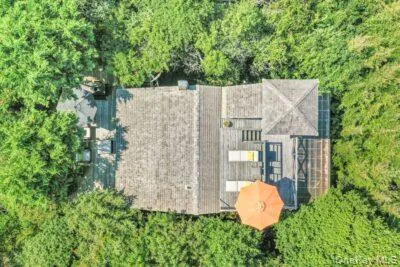 an aerial view of a house with garden space and trees all around